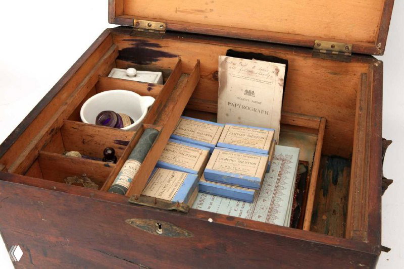 Внутренний вид деревянного ящика с отсеками, где лежат пачки папирографической бумаги, коробочки и инструменты для печати копий.