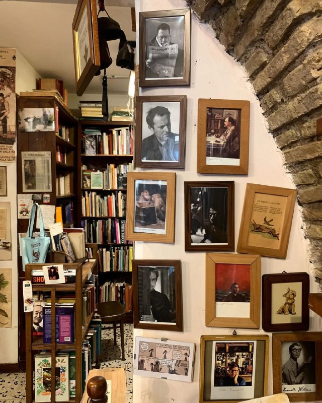 Коллаж из рамок и фотографий на стене над книжными полками в Open Book: сочетание литературы и визуальных артефактов формирует уникальный характер пространства.