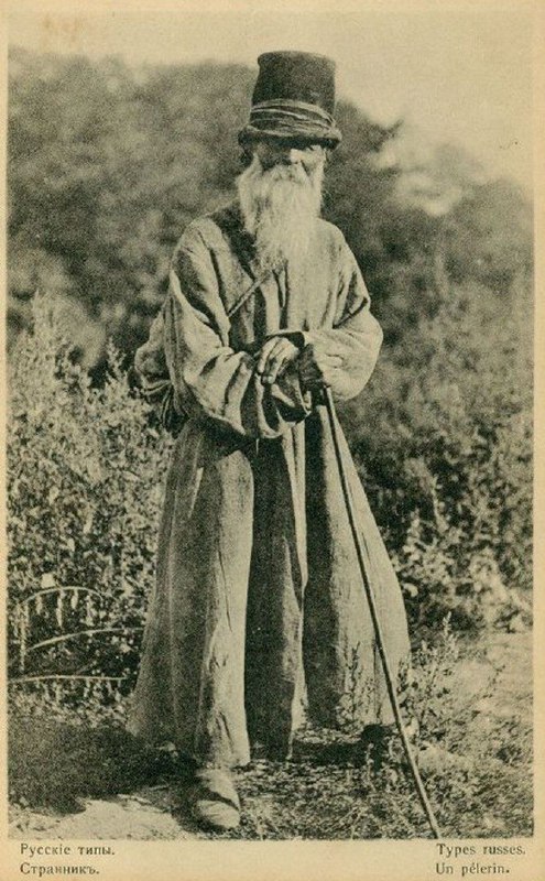 Пожилой мужчина с длинной бородой в традиционной одежде и тростью; портретная открытка, подчёркивающая образ старого крестьянина.