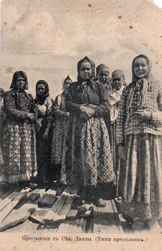 Группа женщин в праздничных национальных костюмах, стоящих на причале; монохромная открытка с подписью о типах народов России.