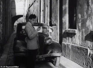 Мужчина у ретро‑автомобиля в узкой улочке держит бумагу или устройство; кадр демонстрирует городскую сцену и стилистику конца 1940‑х годов в фильме.