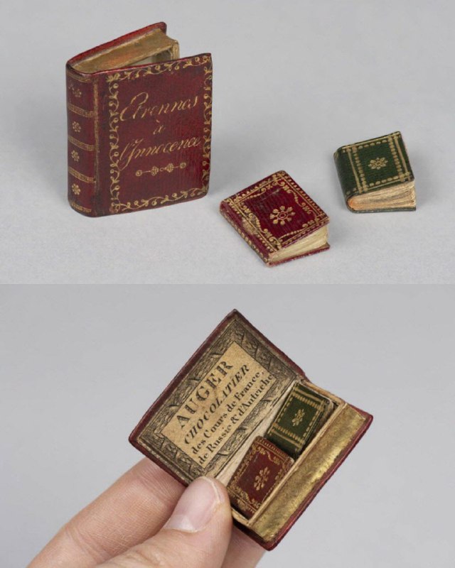 Несколько миниатюрных книг разного оформления: красные и зелёные сафьяновые переплеты с золотым тиснением, одна книга открыта и видна типографская страница.