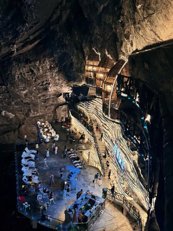 Сцена и ступенчатые ряды полок в пещерном помещении; люди и оборудование, создающие атмосферу мероприятия в магазине.