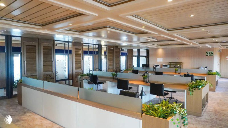 Рабочая или многофункциональная зона на лайнере — столы, зелёные акценты и деловая планировка для встреч и работы в плавании.