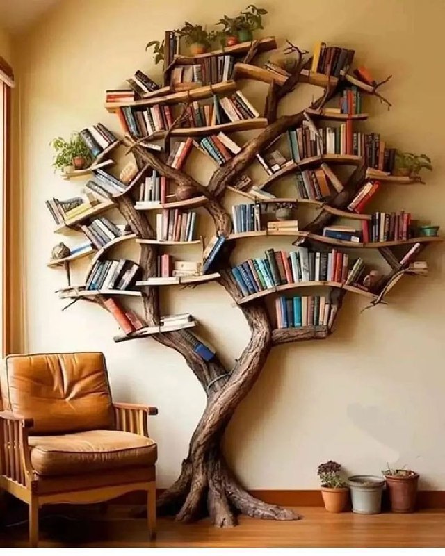 Настенная книжная полка-дерево: ветвящиеся полки, уставленные книгами; рядом кожаное кресло и тёплый интерьер, подчёркивающий домашнюю библиотеку.