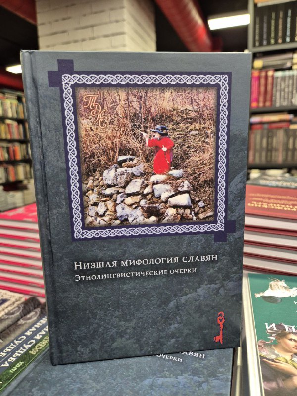 Черный том «Низшая мифология славян» с фотографией на обложке, стоящий среди академических изданий в книжном магазине.