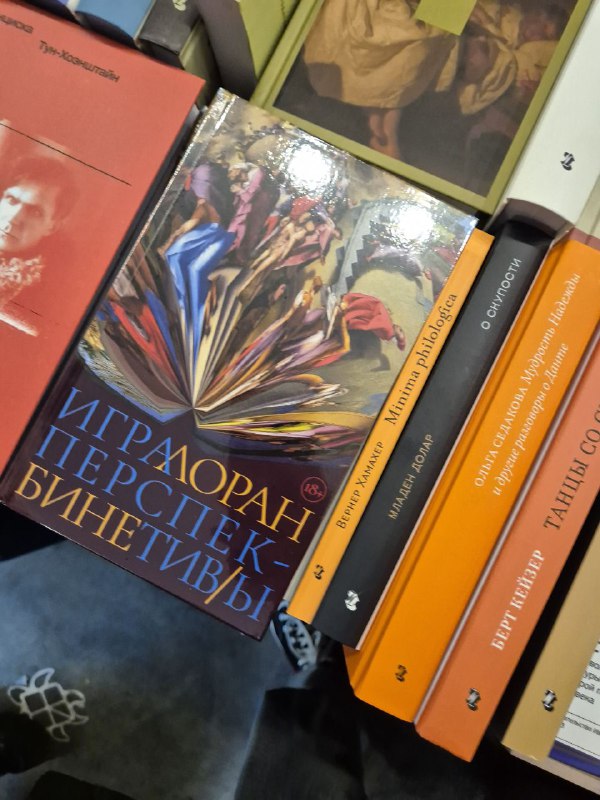 Стол с художественными книгами и разноцветными обложками на прилавке ярмарки Rassvet, видны крупные переплеты и соседние тома.