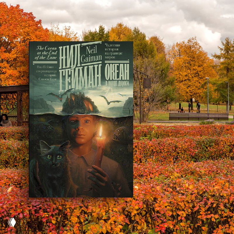 Обложка книги «Океан в конце дороги» Нила Геймана на фоне осеннего парка: тропинка в листьях и пасмурное небо над деревьями.