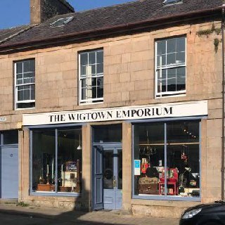 Фасад магазина «The Wigtown Emporium» в Уигтауне: светлая вывеска, большие витрины и каменный фасад, типичный для официального книжного города.