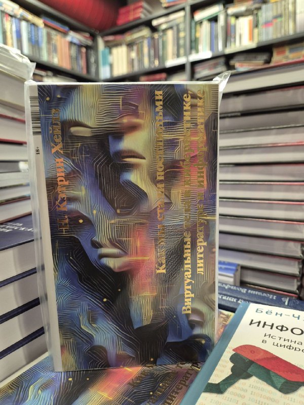 Снимок книги с абстрактной голографической обложкой на прилавке; изображение отражает современное оформление и стеллажи книг за ним.