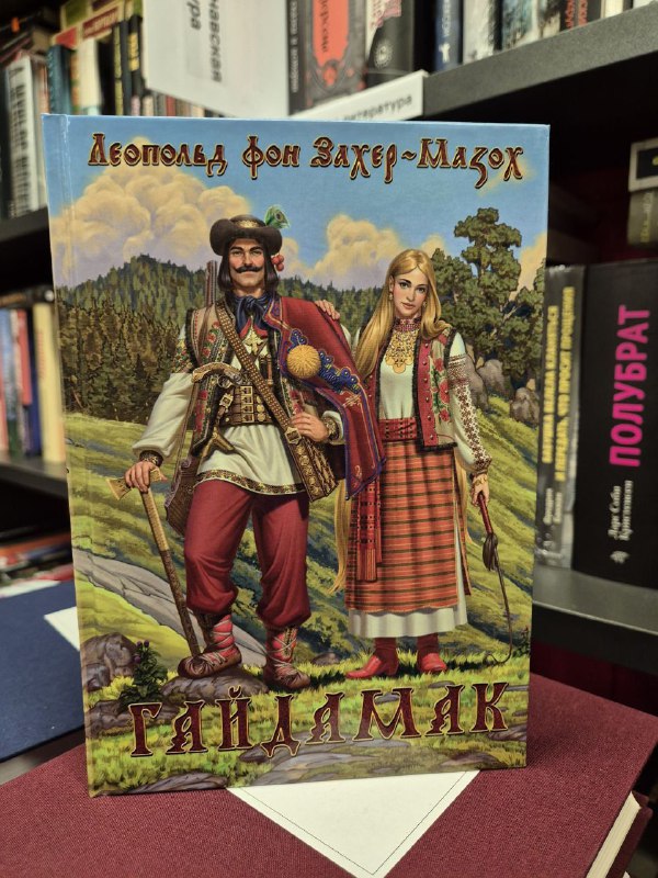 Обложка сборника Захер‑Мазоха «Гайдамак» с иллюстрацией в национальном стиле, книга лежит на прилавке среди других изданий.