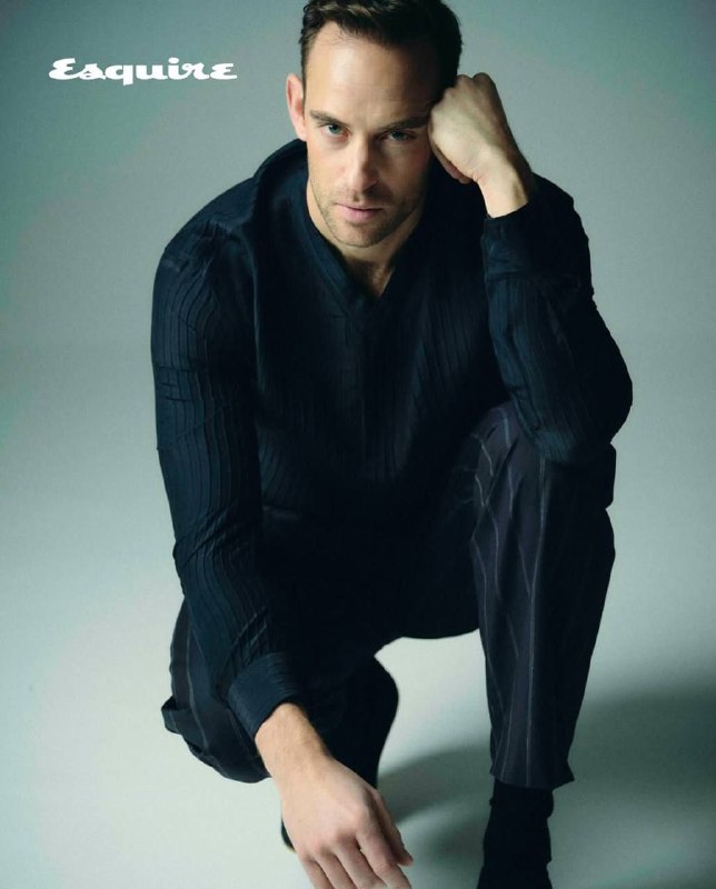 Фотосъемка в студии: Жоэль Диккер в темной рубашке, сидящая поза в полный рост, нейтральный фон и спокойная тональность снимка.