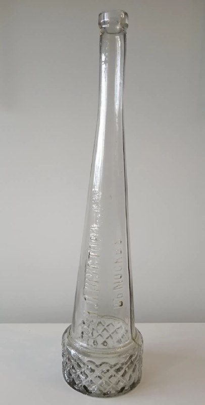Высокая винтажная стеклянная бутылка с рельефным дном и гладким горлом, возможная амбалажная деталь для коньяка начала XX века.