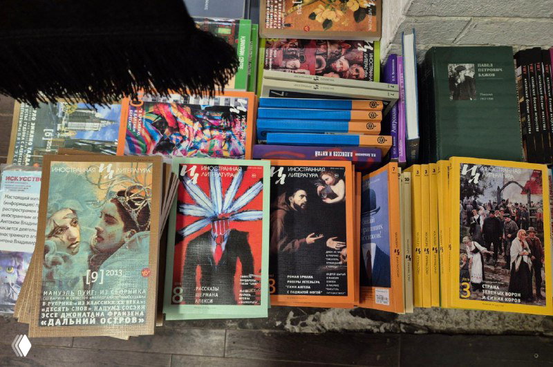Стопка архивных номеров журнала «Иностранная литература» и другие журналы, разложенные на столе в книжном ларьке