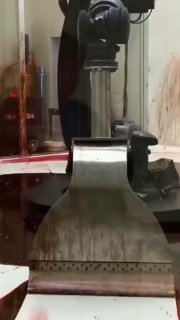 Кадр видео с промышленным манипулятором и резервуаром густой красной жидкости; механическое движение создает тревожную и гипнотическую сцену.