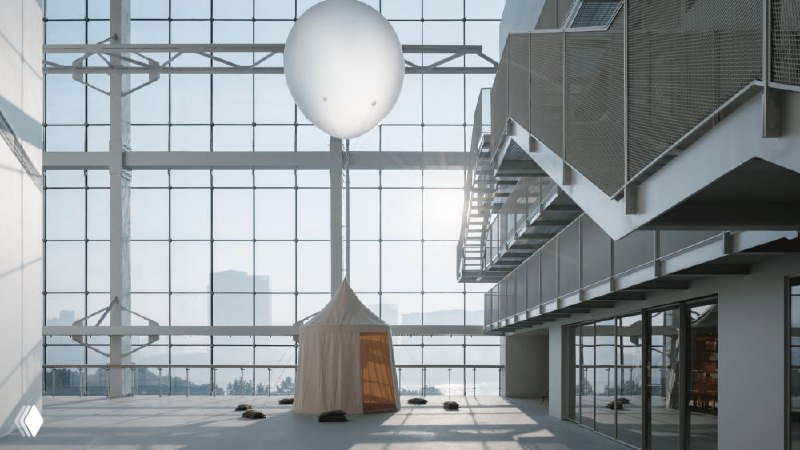 Внутренний атриум с высоким остеклением, инсталляциями и деревянным павильоном — светлое пространство перед основной частью библиотеки.