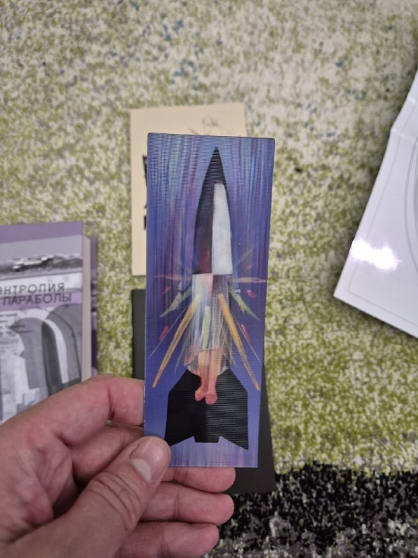 Другая сторона закладки: изображение ракеты с цветными лучами и геометрией, снятое на фоне материалов набора