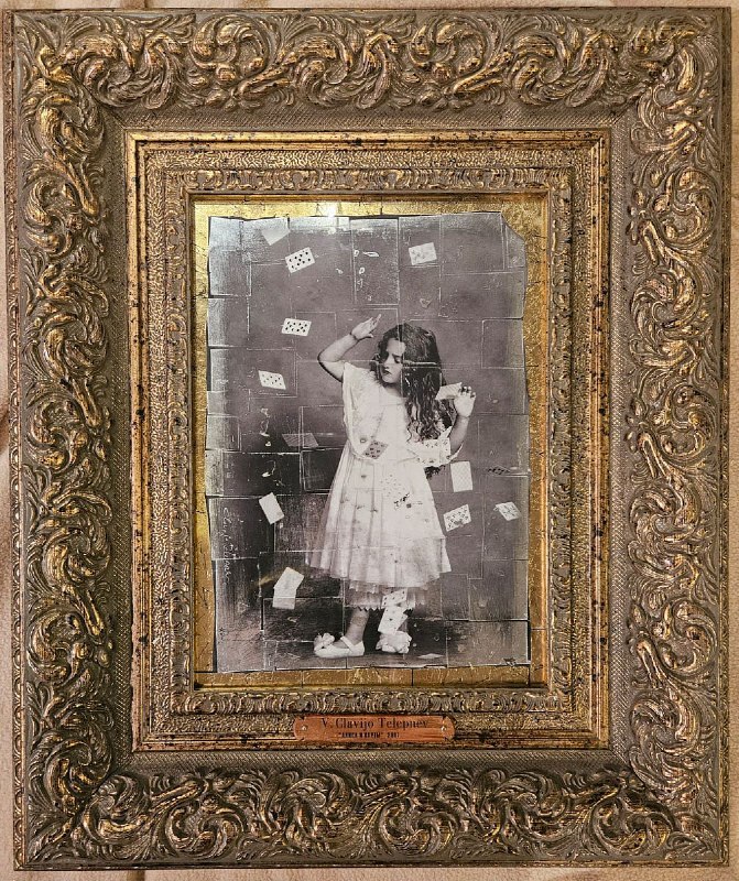 Старинная фотопортретная репродукция девочки в декоративной рамке, на снимке разлетаются карты — архивный материал экспозиции о «Алисе».