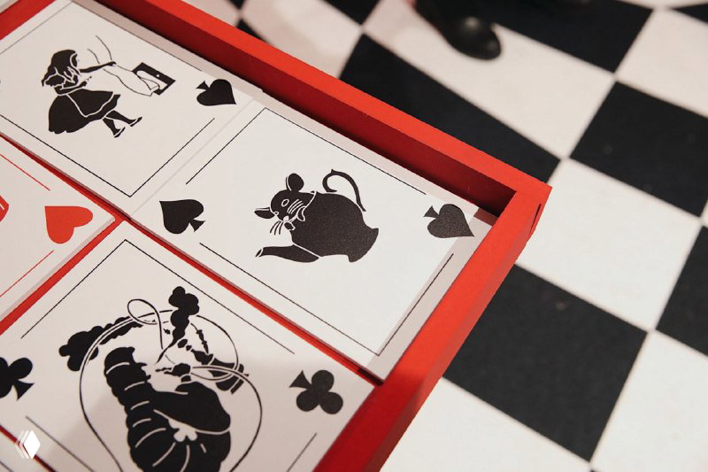 Крупный план декоративной коробки с карточками: чёрно‑белые силуэты персонажей и шахматная тема, элемент сценографии и оформления экспозиции.