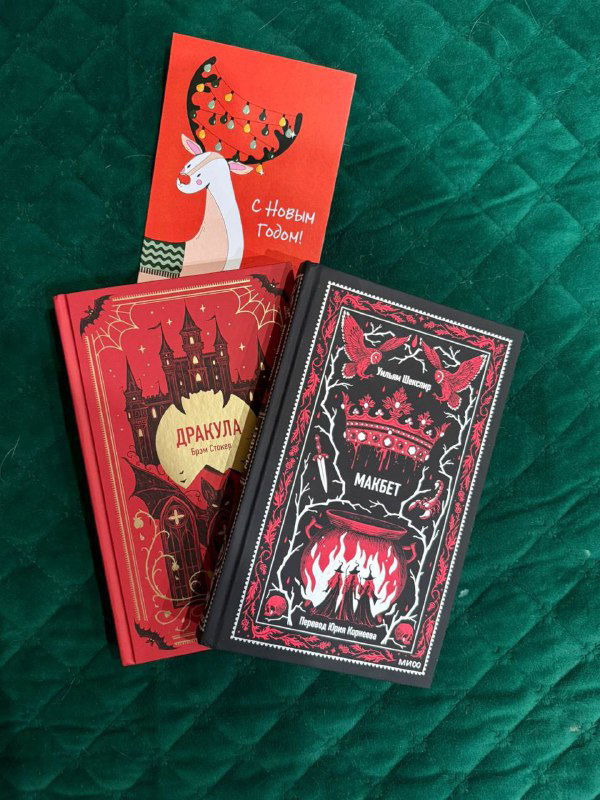 Две декоративные красные книги рядом с открыткой на зелёном бархатном фоне — праздничный кадр с акцентом на оформление подарков.