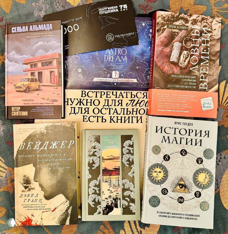 Разложенные на ковре книги разного формата: подборка подарков и читаемых авторов, видны обложки и заголовки в общей композиции.