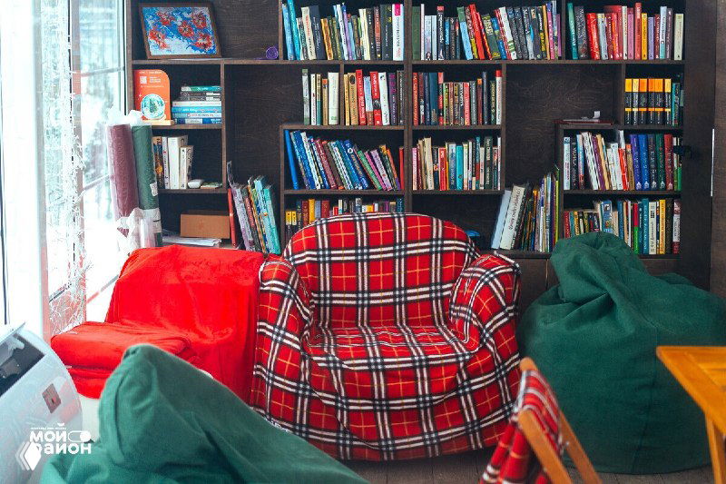 Уютный угол с креслом и книжной полкой в павильоне — пример зоны, где можно почитать или обменяться книгами по принципу буккроссинга.