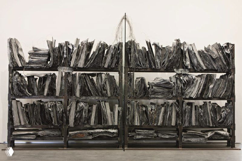 Скульптурная инсталляция: ряды тяжёлых 'книг' и полок из тёмного материала, текстурные листы как объекты памяти и утраты.