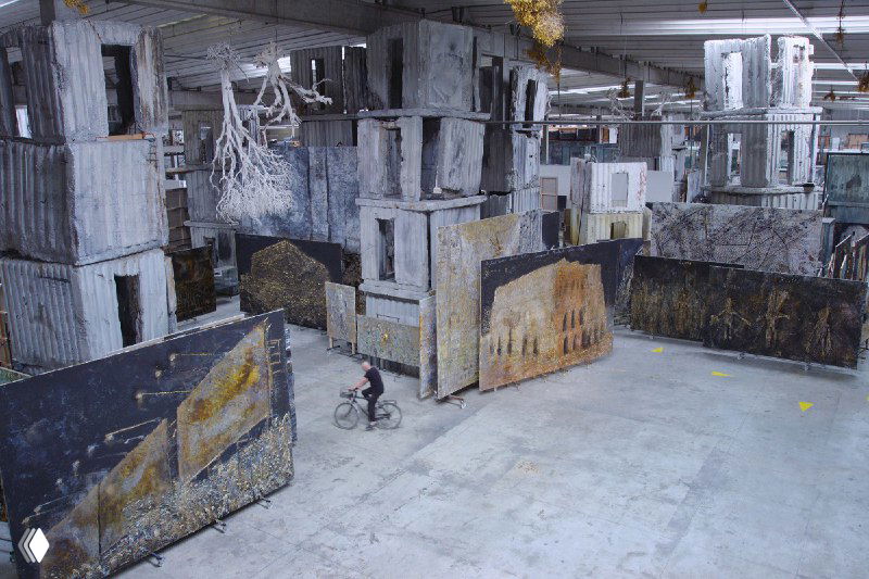 Интерьер большой мастерской/ангара с масштабными инсталляциями и индустриальной архитектурой — территория производства работ художника.