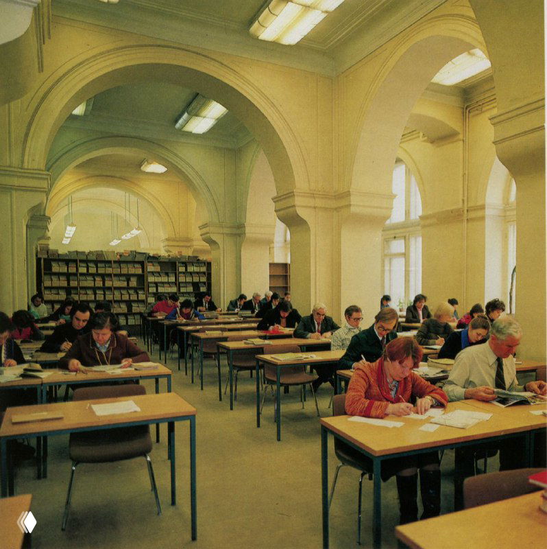 Читальный зал с арочными окнами и столами, посетители работают за столами — вид исторического читального зала библиотеки в здании на Кузнецком мосту.