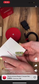 Превью вертикального видео: рука держит инструкцию рядом с зарядным устройством, кабелем и круглой подставкой на столе.