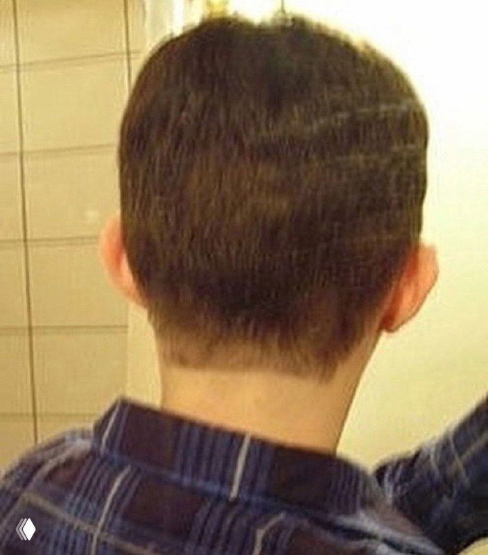 Задняя часть головы и шея в зеркале: короткая стрижка, видна шея и верхняя часть рубашки, бытовой интерьер фона.