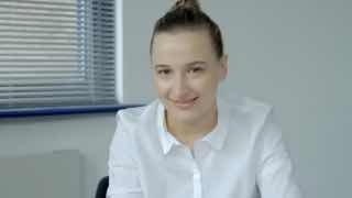 Улыбающаяся женщина в белой рубашке в офисе на фоне жалюзи — деловой портрет для иллюстрации мыслей о бизнесе.