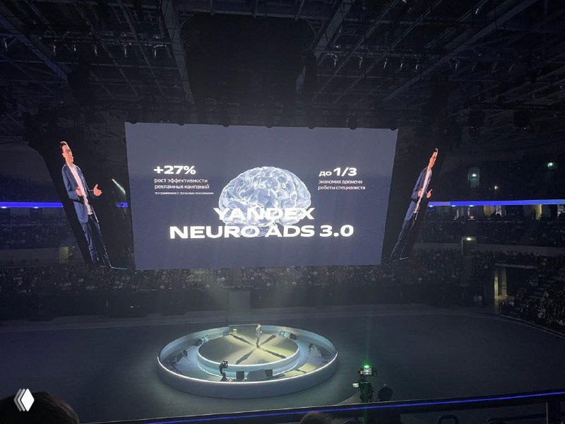 Крупный кадр экрана на сцене: слайд с надписью NEUROADS 3.0 и статистикой, видна круглая платформа на сцене и затемнённый зал.