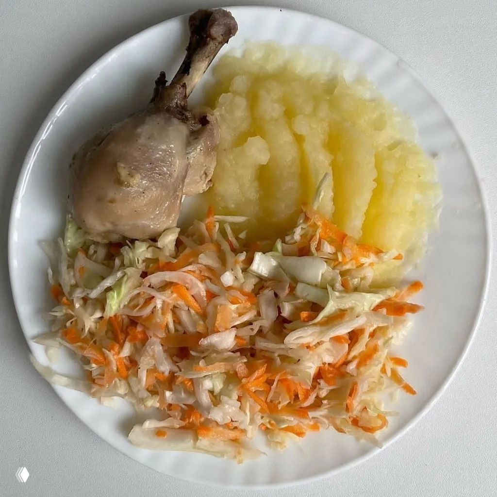 Порция с куриной голенью, картофельным пюре и квашеной капустой на белой тарелке — классическое сочетание для сытного обеда.