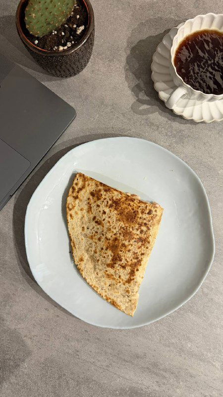 Свернутая тортилья на белой тарелке рядом с чашкой кофе — простая тортилья с начинкой из копченой курицы или индейки.