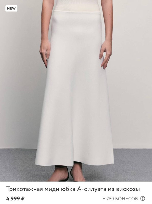 Трикотажная миди-юбка А‑силуэта белого цвета, показана длина и крой спереди на манекене/модели — полезно для оценки сочетания с верхом и обувью.