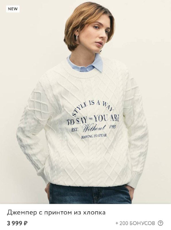 Светлый свитер с принтом на груди на модели, крупный план демонстрирует фактуру трикотажа и расположение графики, который спасает образ с джинсами.