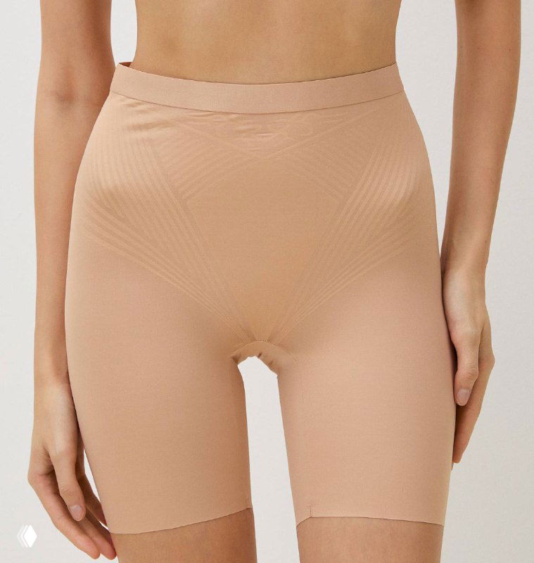Модель в корректирующих бежевых шортах средней длины, пример «комбинезона» для сглаживания силуэта под платьем.