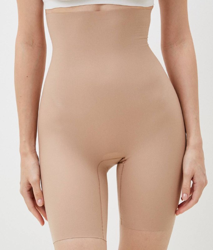 Длинные корректирующие бежевые шорты на модели, демонстрация эффекта утяжки и скрытия линий под одеждой.