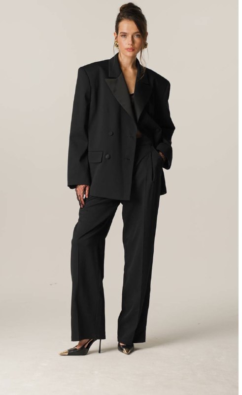 Модель в чёрном костюме: свободный жакет и широкие брюки, полный образ на модели, демонстрация пропорций и стиля костюма.