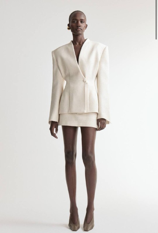 Модель в кремовом костюме: светлый жакет и мини‑юбка, сочетание костюма с акцентом на фактуру и длину, пример нежного варианта костюма.