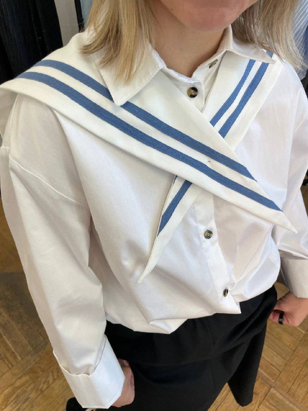 Крупный план воротника-гюйс на белой рубашке: видимый декоративный элемент, который можно носить поверх свитера или рубашки.