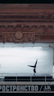 Человек в стойке на руках в просторном зале с резным потолком и надписью «ПРОСТРАНСТВО» на стене — акцент на балансе и контроле.