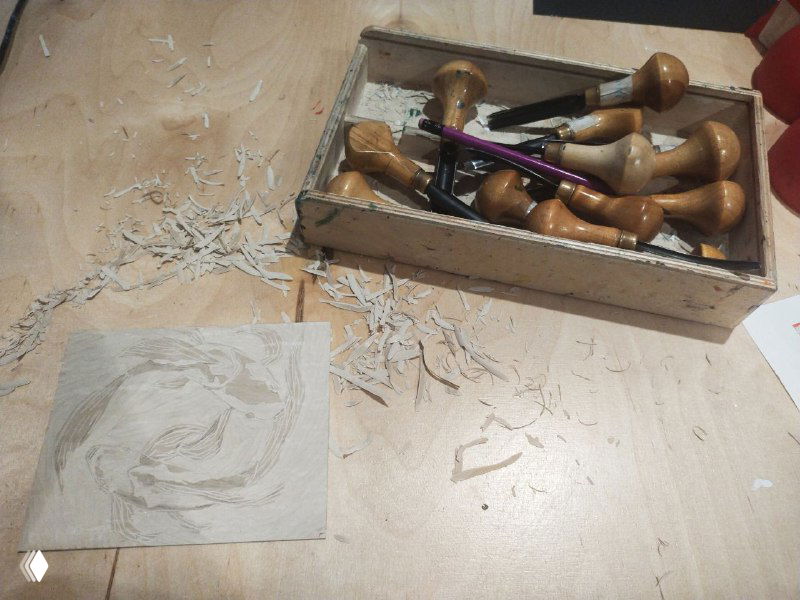 Процесс резьбы по пластине: обрезки материала вокруг, пластиковая либо полимерная пластина и набор резцов на деревянном столе.