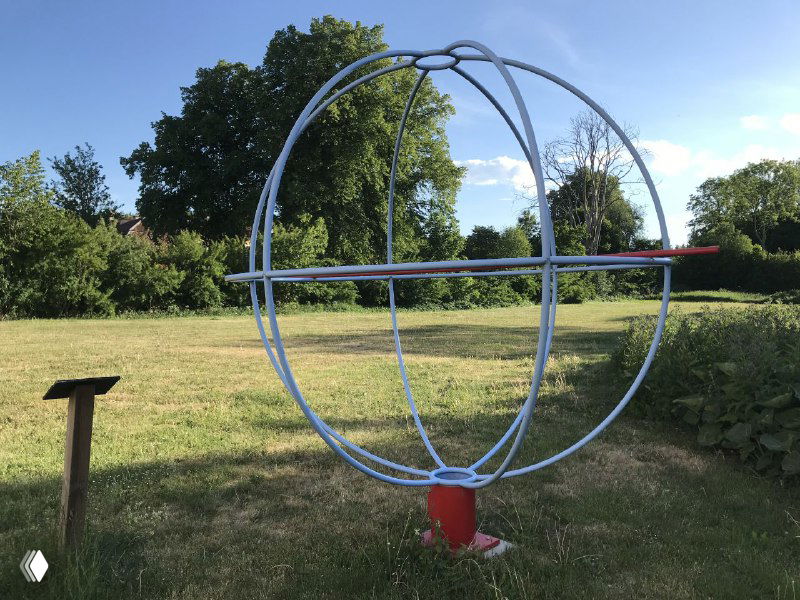 Металлический каркас в виде сферы на поле — простая художественная конструкция, используемая для обозначения одного из объектов модели Солнечной системы.