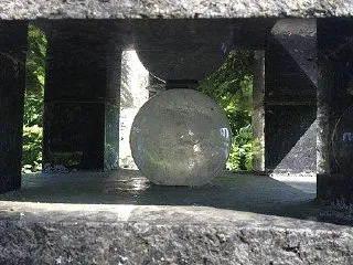 Прозрачный стеклянный шар, установленный в нише каменной композиции — эстетический маркер для одного из спутников или малых тел модели.