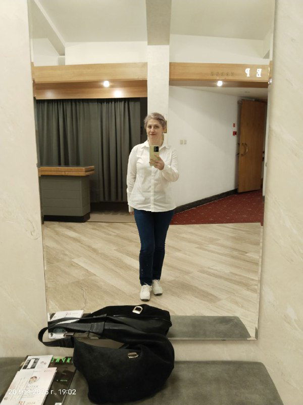 Зеркальное селфи в фойе театра: автор снимка в светлой рубашке, на полу сумка и программа спектакля — кадр после спектакля.