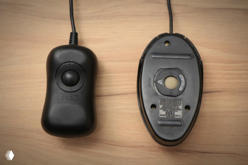 Крупный план японской версии мыши Sega Mouse и её основания с видимым переворачиваемым шариком-трекболом и контактными площадками снизу.