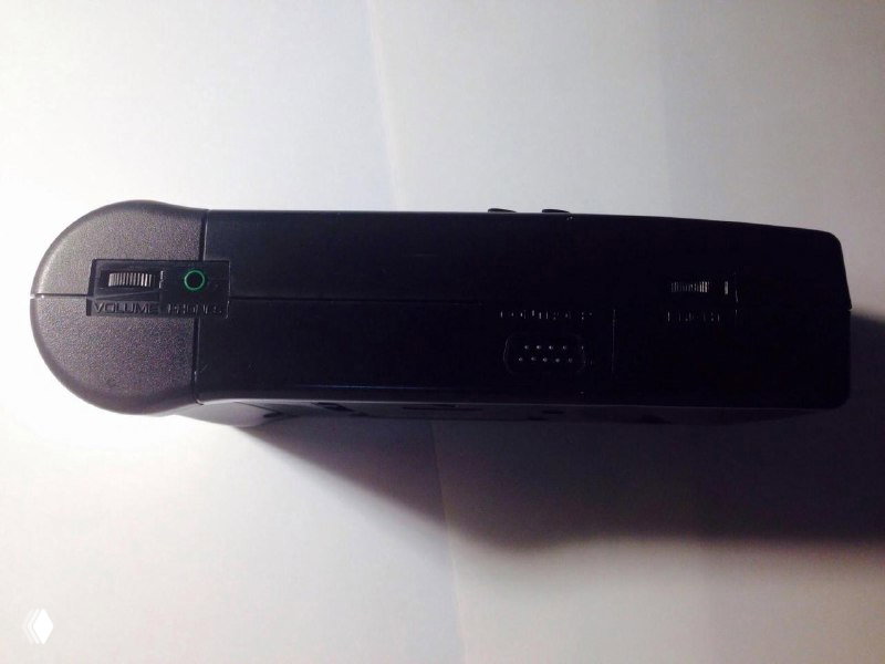 Вид сбоку SEGA Nomad на белом фоне: разъёмы для подключения, гнездо для наушников и характерный профиль пластиковой портативной консоли 90-х годов.