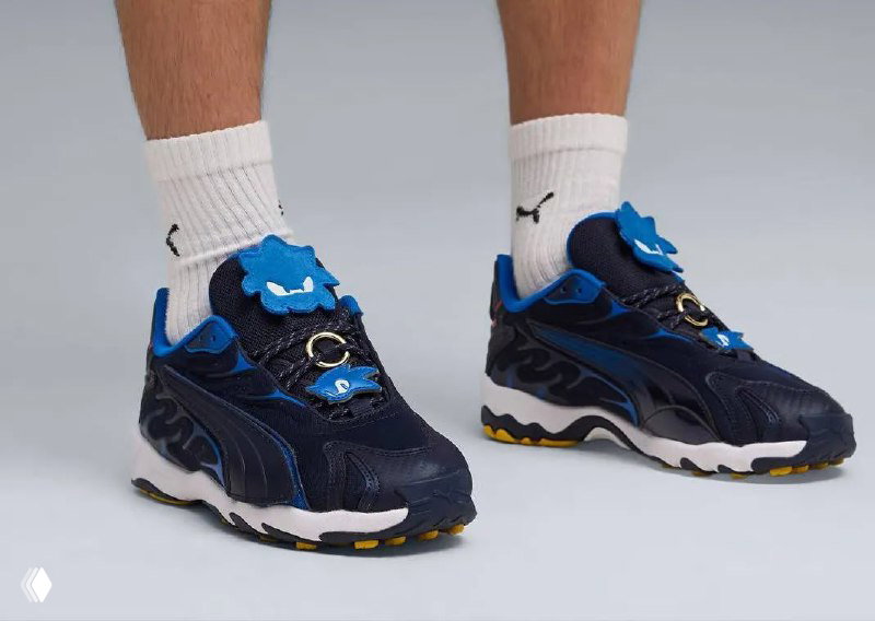 Синие кроссовки Puma из коллаборации Sonic Racing на ногах модели с белыми носками и логотипом Puma — вид в профиль, подчёркивающий дизайн подошвы.